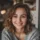 Jeune femme souriante avec pull gris.