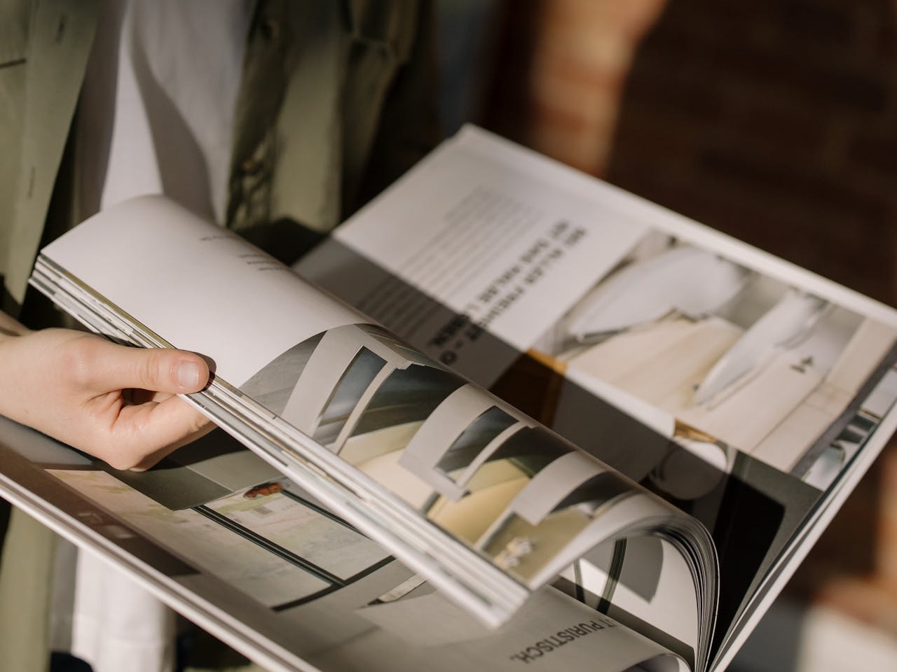 Close-up of hands turning pages in a modern architecture magazine.