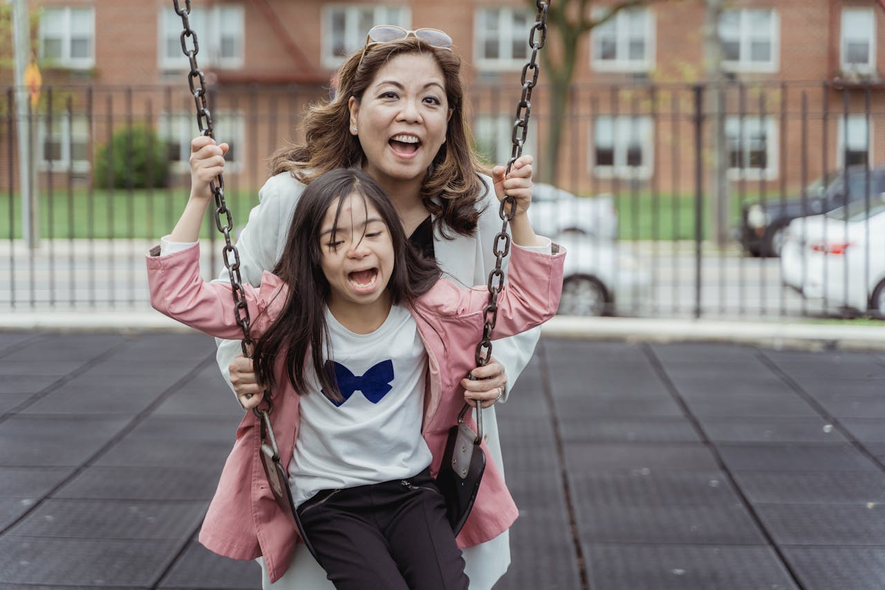 our-story Joyful moment of mother and daughter playing on a swing in an urban park.