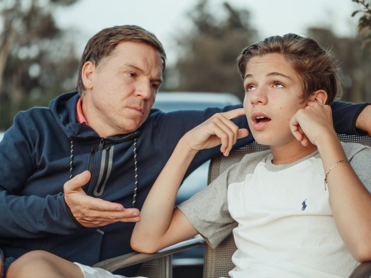 A father and teenage son having an intense conversation, capturing the essence of family dynamics and communication.